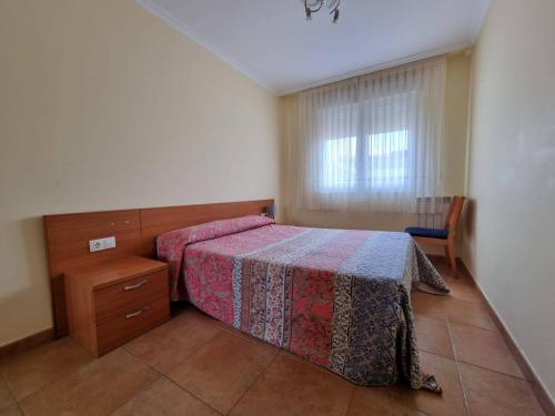 a bedroom with a bed and a dresser and a window at Apartamento en Playa Rapadoira in Foz