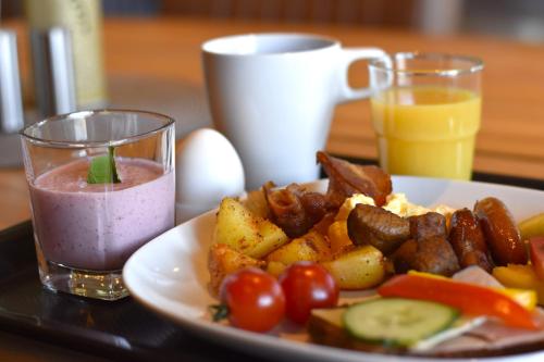 un piatto di cibo con bevanda rosa e un piatto di cibo con pomodori di Munken Hotell & Konferens a Mönsterås