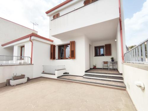 Dieses weiße Haus verfügt über einen Balkon und eine Terrasse. in der Unterkunft Casa Vacanza Luna in SantʼAntìoco