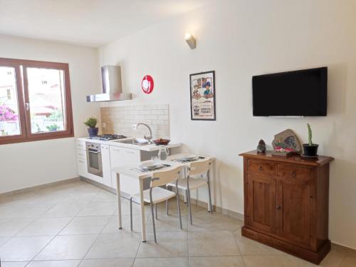 eine Küche mit einem Tisch und einem TV an der Wand in der Unterkunft Casa Vacanza Luna in SantʼAntìoco