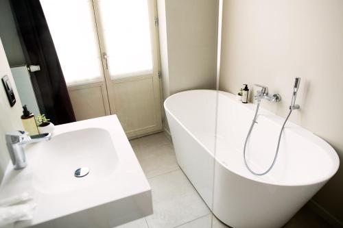 a white bathroom with a tub and a sink at Hôtel de la Poste in Ellezelles