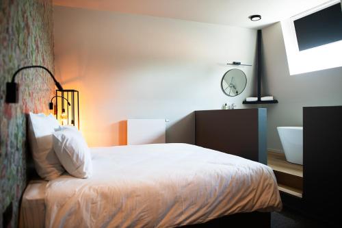 a bedroom with a bed and a bathroom with a sink at Hôtel de la Poste in Ellezelles