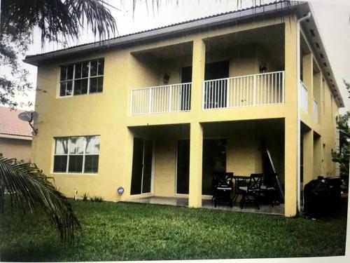 Cette grande maison jaune dispose d'une terrasse couverte. dans l'établissement Relaxation Zone, à West Palm Beach