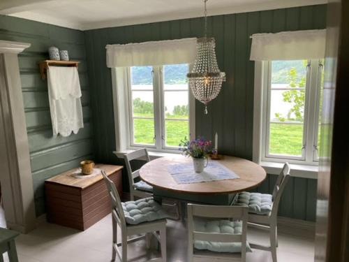 ein Esszimmer mit einem Tisch, Stühlen und Fenstern in der Unterkunft Steinsvoll Gård in Vang I Valdres