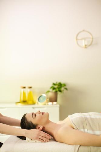 a woman laying on a bed with her eyes closed at Magnus Resort in Szczyrk