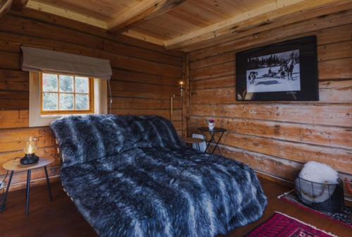 a bedroom with a bed in a log cabin at Stokke Gård Burglamping in Stjoerdal