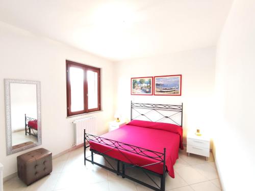1 dormitorio con cama roja y espejo en Casa Vacanza Nuvola, en SantʼAntìoco