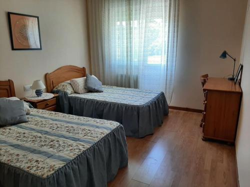1 dormitorio con 2 camas, escritorio y ventana en Lhamo Mandala House, en Pontevedra