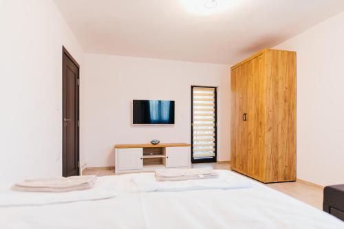 una camera bianca con letto e armadietto in legno di The Home Sweet Home a Gheorgheni