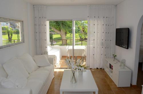 a living room with a white couch and a tv at Apartamento IGUAZU in Playa del Ingles