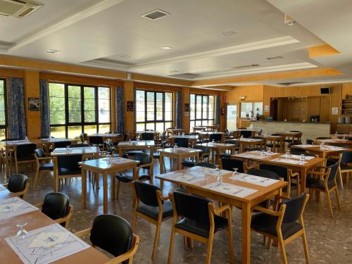 un comedor con mesas, sillas y ventanas en Hotel Restaurante La Cañada, en Fuencaliente de Lucio