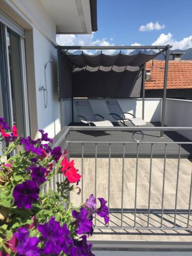 a balcony with purple flowers and a table and chairs at Da Tosca in Gravellona Toce