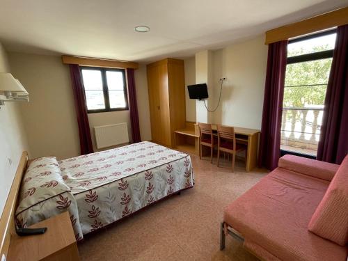 a bedroom with a bed and a table and a couch at Hotel Restaurante La Cañada in Fuencaliente de Lucio