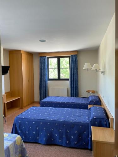 a hotel room with two beds and a window at Hotel Restaurante La Cañada in Fuencaliente de Lucio