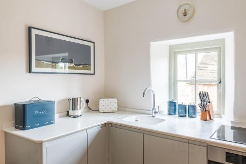 a white kitchen with a sink and a window at Luxury cottage in Stamford featured in the Sunday Times, best place to live in Stamford