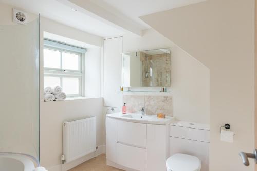 a white bathroom with a sink and a toilet at Luxury cottage in Stamford featured in the Sunday Times, best place to live in Stamford