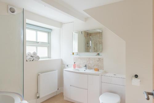 Baño blanco con lavabo y aseo en Luxury cottage in Stamford featured in the Sunday Times, best place to live, en Stamford