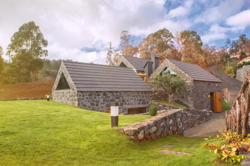 a stone house with a stone wall at Palheiros do Serrado by Real Vision in Estreito da Calheta
