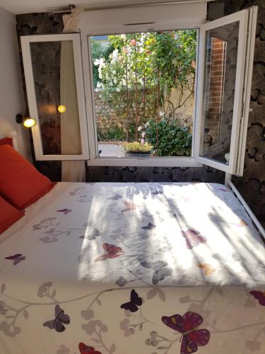 La Rivière Saint SauveurにあるLa tourterelleの花のベッドカバー付きの窓の前のベッド