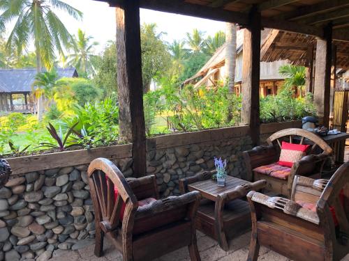 a porch with chairs and a table and a stone wall at On The Mekong Resort in Luang Prabang