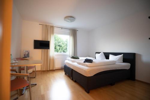 a bedroom with a bed and a table and a window at Haus Hotel Inter in Buxtehude