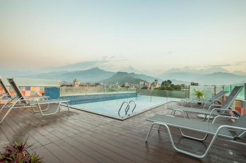 a deck with lounge chairs and a swimming pool at Dahlia Boutique Hotel in Pokhara