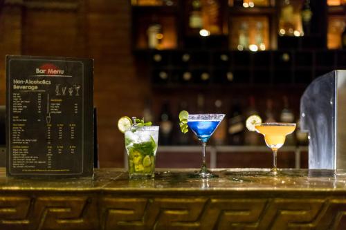 three cocktails sitting on top of a bar at Dahlia Boutique Hotel in Pokhara