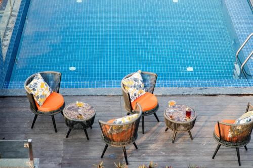 un grupo de sillas y mesas junto a una piscina en Dahlia Boutique Hotel, en Pokhara