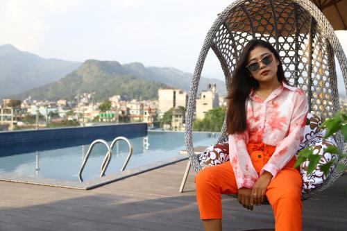 a woman sitting in a swing by the water at Dahlia Boutique Hotel in Pokhara