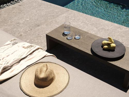 a hat sitting on a table next to a pool at Noima Boutique Hotel Mykonos in Agios Ioannis Mykonos