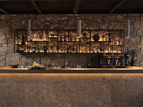 a bar with a stone wall and a counter with a plate of food at Noima Boutique Hotel Mykonos in Agios Ioannis Mykonos