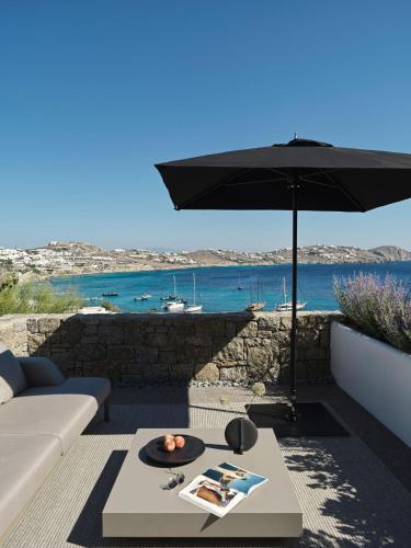 a living room with an umbrella and a table at Noima Boutique Hotel Mykonos in Agios Ioannis Mykonos