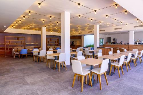a dining room with tables and chairs and a bar at Hotel Cordial Marina Blanca in Playa Blanca