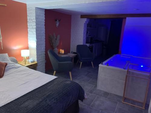 a bedroom with a tub and a bed and chairs at Studio Cosy avec Jacuzzi Privatif et Terrasse in Hazebrouck