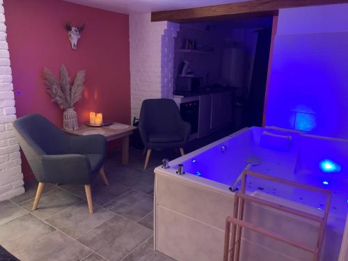 a room with a tub and two chairs and a table at Studio Cosy avec Jacuzzi Privatif et Terrasse in Hazebrouck