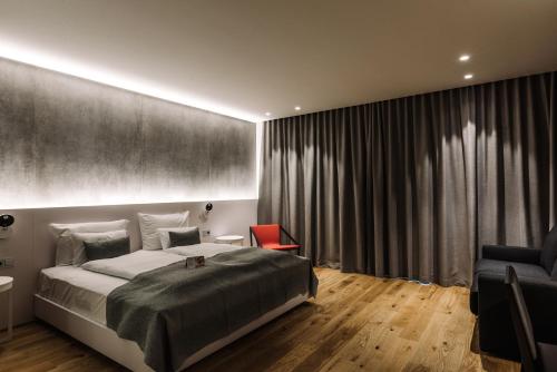 - une chambre avec un grand lit et une chaise rouge dans l'établissement Hotel A, à Celje