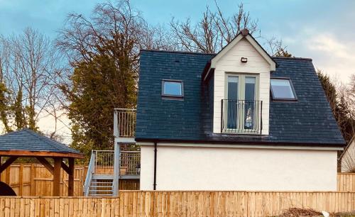 een huis met een zwart dak boven een hek bij 'Wardlaw View' Luxury studio apartment with stunning view in Kirkhill
