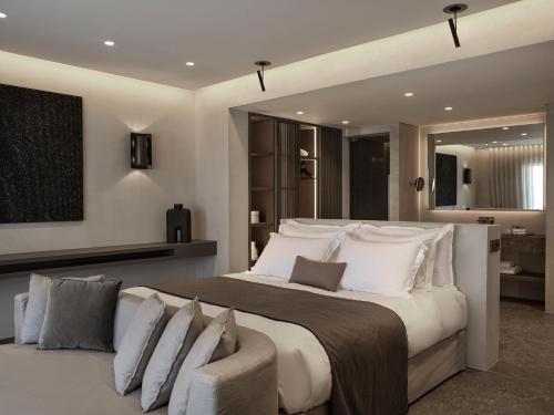 een grote slaapkamer met een groot bed en een bank bij Noima Boutique Hotel Mykonos in Agios Ioannis Mykonos
