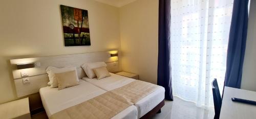 a bedroom with a white bed and a window at ESPERANCE HOTEL in Nice