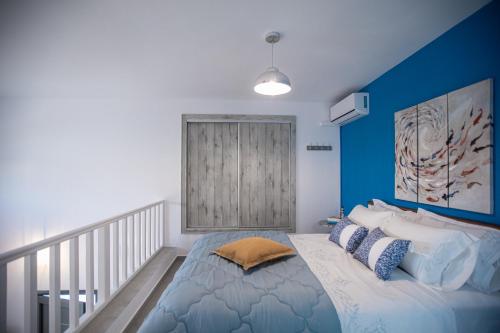 a bedroom with a bed with a blue accent wall at Amarynthos Maisonettes in Amarynthos
