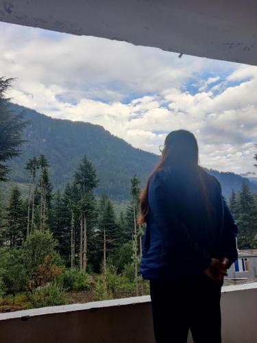 a woman looking out of a window at the mountains at Safar Hostel Manali in Manāli