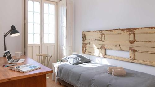 a bedroom with a bed and a desk with a laptop at RUN Aveiro in Aveiro