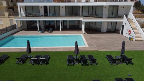 a swimming pool with lawn chairs and umbrellas at AlgarPapa Rooms in Armação de Pêra