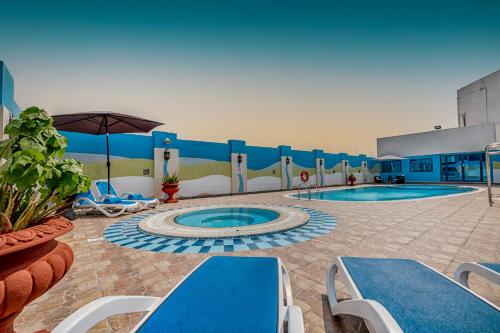 a swimming pool with chairs and an umbrella at THE PARK HOTEL Formerly Al Jawhara Gardens in Dubai