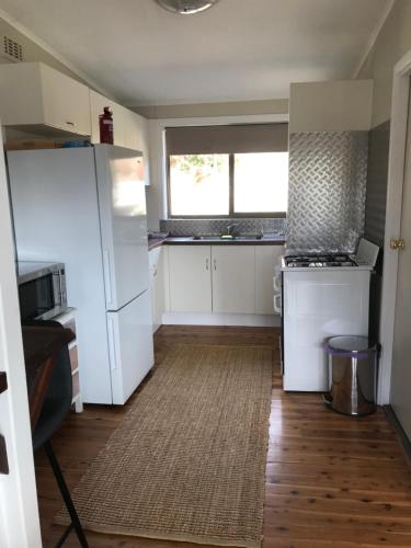 a kitchen with white appliances and a large window at 3 Bedroom Lakeview Cottage with Drying/Bike Room in Jindabyne