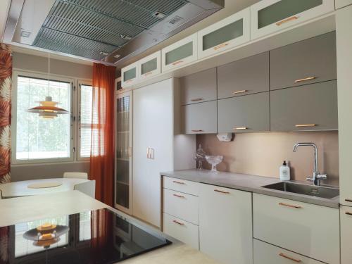 a kitchen with white cabinets and a sink and a window at Lovely cityhome in Rovaniemi