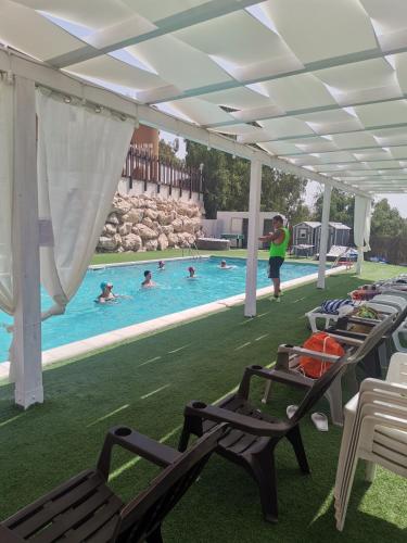 a pool with chairs and people in the water at Imperial Park in Raffadali
