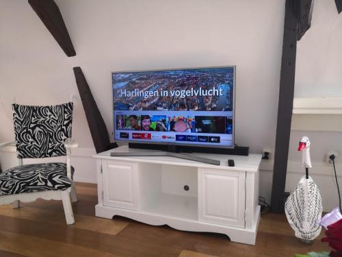 a television on a white stand in a living room at WitteZwaan in Harlingen