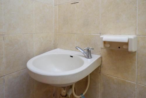 La salle de bains carrelée est pourvue d'un lavabo blanc. dans l'établissement Hotel Widodo 1 Parangtritis RedPartner, à Girijati