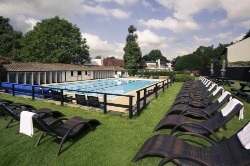 a large swimming pool with chairs and a row at Mercure Box Hill Burford Bridge Hotel in Dorking